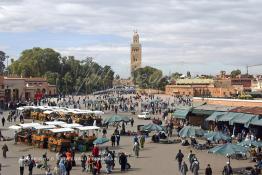 Image du Maroc Professionnelle de  Les calèches de jus d'orange sont bien alignés sur La mythique place Jemaa El Fana, avec ses charmeurs de serpents, lieu incontournable de Marrakech, la ville touristique du Maroc, Dimanche 27 Février 2005, au fond le minaret de la Koutoubia. (Photo / Abdeljalil Bounhar) 